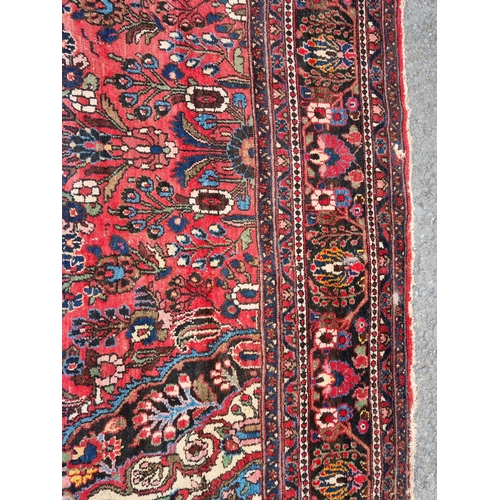 655 - A large Persian woollen Carpet with central cream diamond shaped flower head within red ground with ... 