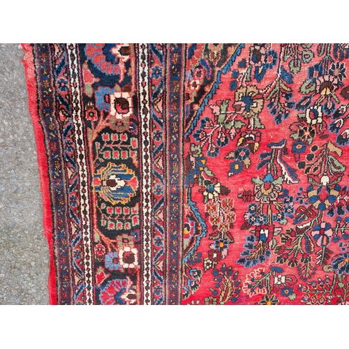 655 - A large Persian woollen Carpet with central cream diamond shaped flower head within red ground with ... 