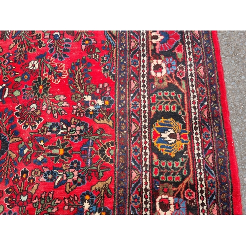 655 - A large Persian woollen Carpet with central cream diamond shaped flower head within red ground with ... 