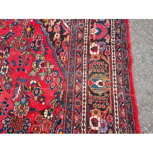 655 - A large Persian woollen Carpet with central cream diamond shaped flower head within red ground with ... 