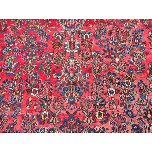 655 - A large Persian woollen Carpet with central cream diamond shaped flower head within red ground with ... 