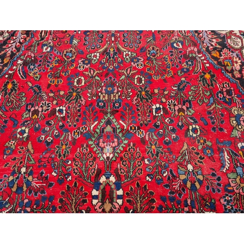 655 - A large Persian woollen Carpet with central cream diamond shaped flower head within red ground with ... 