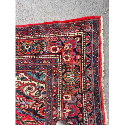 655 - A large Persian woollen Carpet with central cream diamond shaped flower head within red ground with ... 