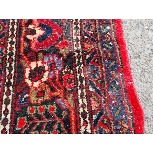 655 - A large Persian woollen Carpet with central cream diamond shaped flower head within red ground with ... 