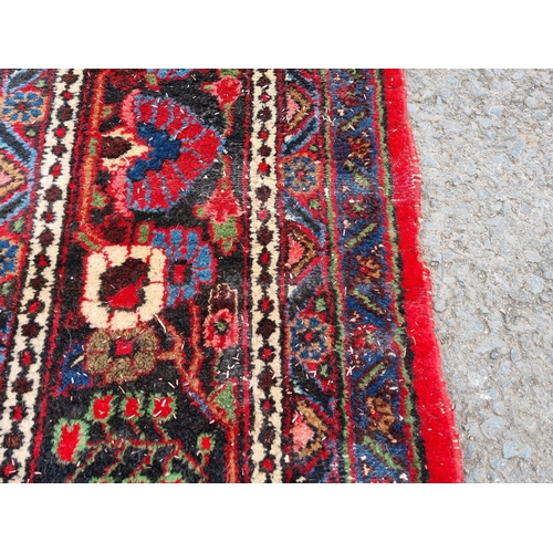 655 - A large Persian woollen Carpet with central cream diamond shaped flower head within red ground with ... 