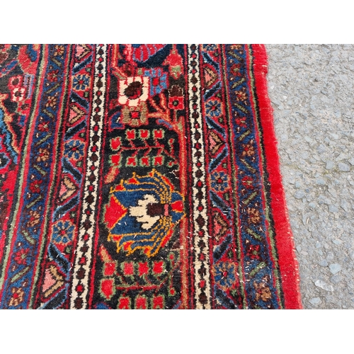 655 - A large Persian woollen Carpet with central cream diamond shaped flower head within red ground with ... 