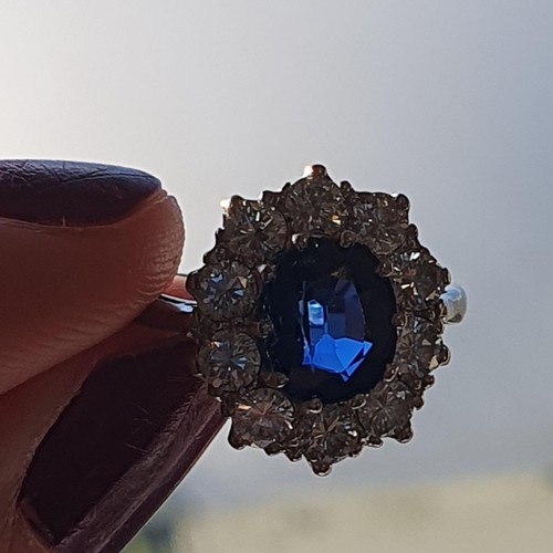 160 - A mid-century Sapphire and Diamond Cluster ring, claw-set oval mixed-cut sapphire, surrounded by ten... 