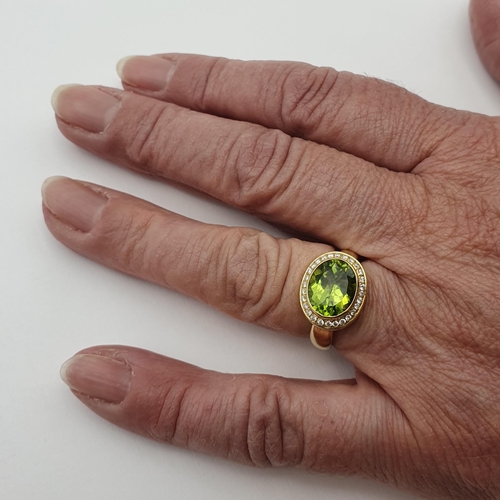 215 - A Peridot and Diamond Dress Ring by Kiki McDonough, rubover-set oval mixed-cut peridot surrounded by... 