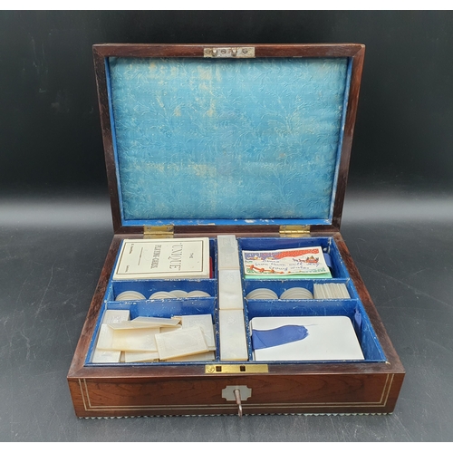53 - A 19th century rosewood Games Box with mother of pearl inlay to the lid depicting playing cards, con... 