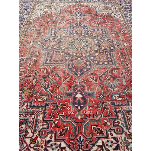 72 - A bordered Persian Carpet with medallion and corner design in blue, etc on a red ground, 11ft 8in x ... 