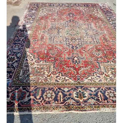 72 - A bordered Persian Carpet with medallion and corner design in blue, etc on a red ground, 11ft 8in x ... 