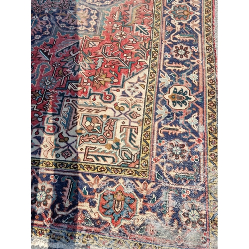 72 - A bordered Persian Carpet with medallion and corner design in blue, etc on a red ground, 11ft 8in x ... 
