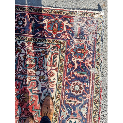 72 - A bordered Persian Carpet with medallion and corner design in blue, etc on a red ground, 11ft 8in x ... 