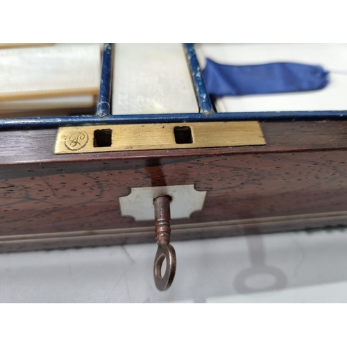53 - A 19th century rosewood Games Box with mother of pearl inlay to the lid depicting playing cards, con... 