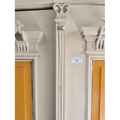 50 - A painted two-door Wardrobe of architectural design, the doors flanked by turned columns and raised ... 