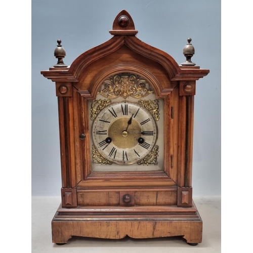 A walnut cased Mantel Clock with gilt mask and spandrels above the ...