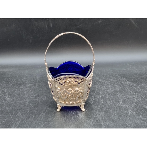 131 - A Continental silver Sugar Basket decorated cherubs and swags, etc, swing handle, blue glass liner. ... 