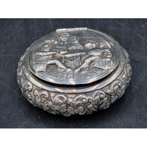 145 - A Dutch silver circular Tobacco Box embossed with figures merrymaking, leafage scrolls etc, 125gms