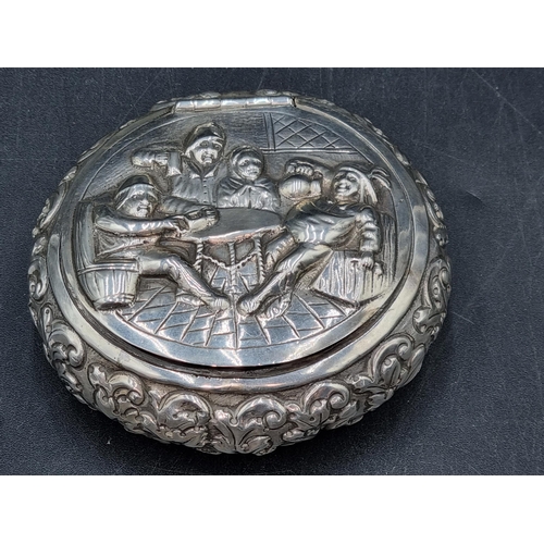 145 - A Dutch silver circular Tobacco Box embossed with figures merrymaking, leafage scrolls etc, 125gms