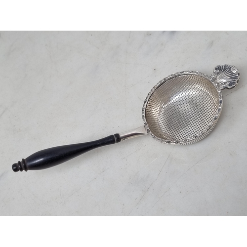 163 - An Elizabeth II silver Tea Strainer with scallop edge and baluster ebonised handle, Birmingham 1981