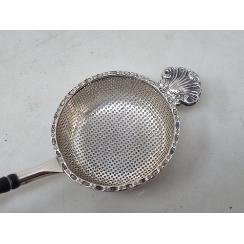 163 - An Elizabeth II silver Tea Strainer with scallop edge and baluster ebonised handle, Birmingham 1981