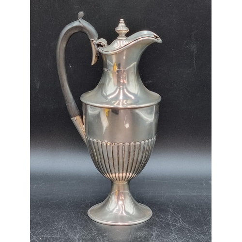 166 - A Victorian silver Claret or Hot Water Jug of semi fluted urn form with hinged lid and ebonised hand... 
