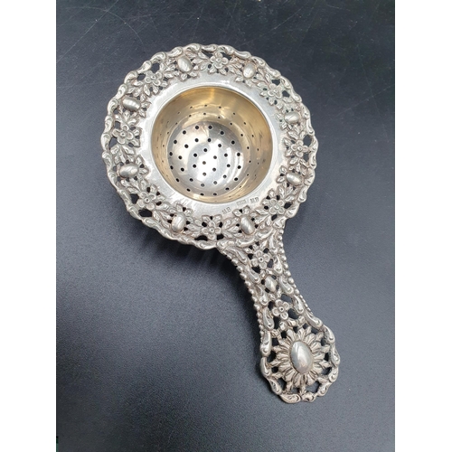 193 - A Continental low grade silver Tea Strainer with floral border, two silver Napkin Rings and two Trin... 