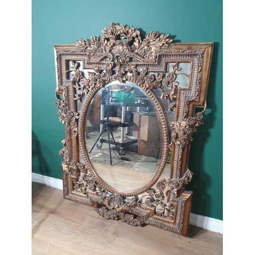 16 - An elaborate gilt framed Wall Mirror with central oval bevelled plate surrounded by floral sprays an... 