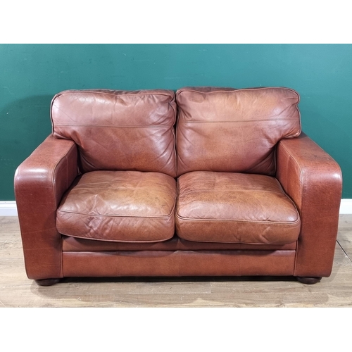 27 - A tan leather two seater Settee, raised on circular bun feet, 4ft 11