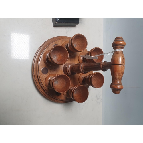 3 - An oak circular Egg Cup Stand with six egg cups and a carrying handle, 9 1/2in H, and an ebonised me... 