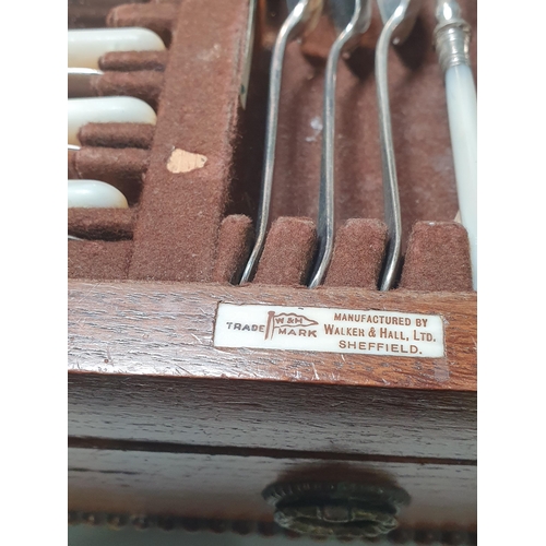34 - An oak Canteen by Walker & Hall containing plated Cutlery and a set of six silver bean-handled Coffe... 