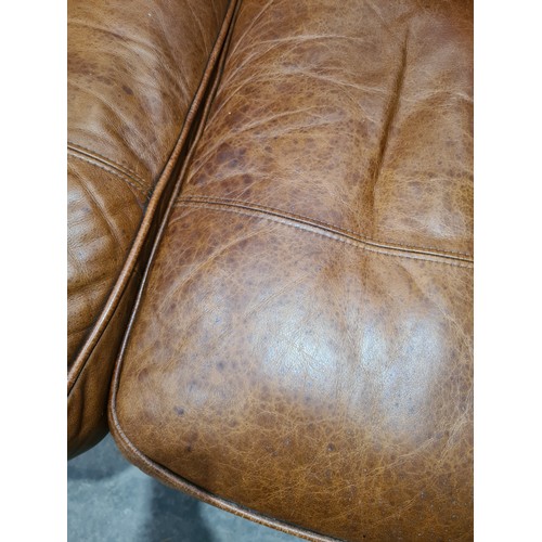 27 - A tan leather two seater Settee, raised on circular bun feet, 4ft 11