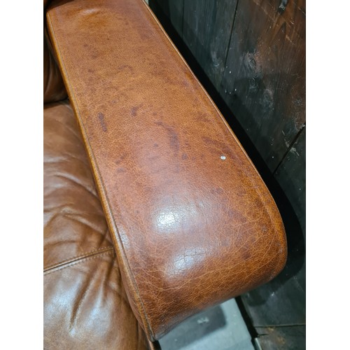 27 - A tan leather two seater Settee, raised on circular bun feet, 4ft 11