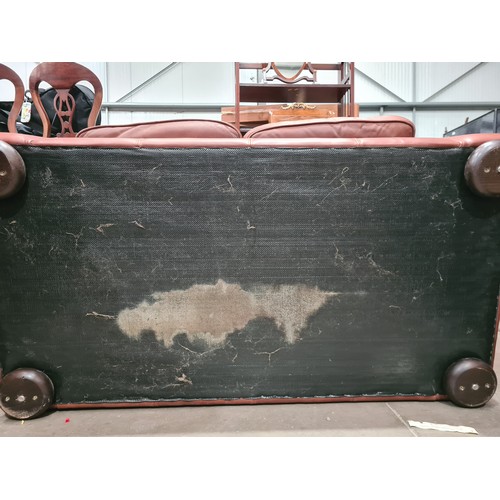 27 - A tan leather two seater Settee, raised on circular bun feet, 4ft 11