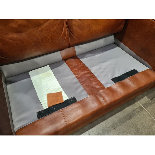 27 - A tan leather two seater Settee, raised on circular bun feet, 4ft 11