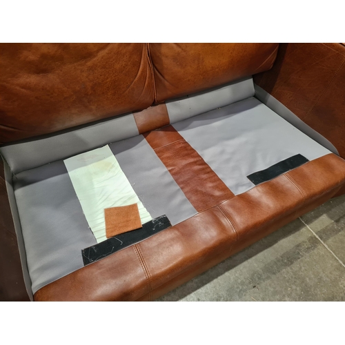 27 - A tan leather two seater Settee, raised on circular bun feet, 4ft 11