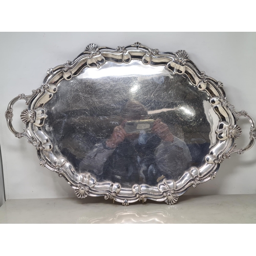 100 - An Edward VII silver large shaped oval two handled Tea Tray with scallop and scroll border on scroll... 