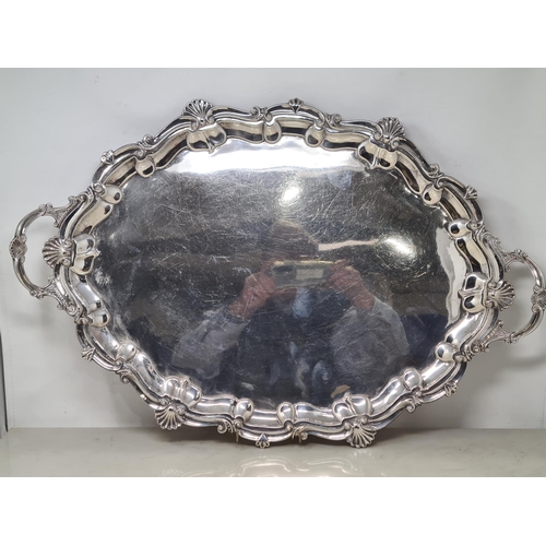 100 - An Edward VII silver large shaped oval two handled Tea Tray with scallop and scroll border on scroll... 