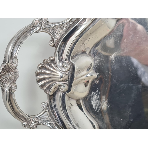 100 - An Edward VII silver large shaped oval two handled Tea Tray with scallop and scroll border on scroll... 
