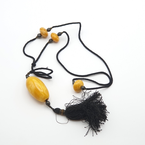 267 - A 1920's Amber type Necklace consisting of black cord strung three beads each between a pair of smal... 