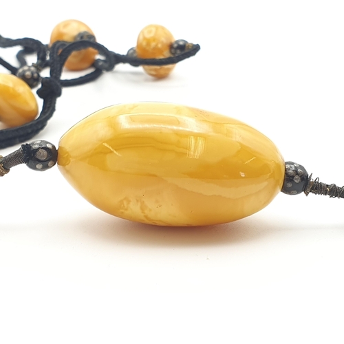 267 - A 1920's Amber type Necklace consisting of black cord strung three beads each between a pair of smal... 