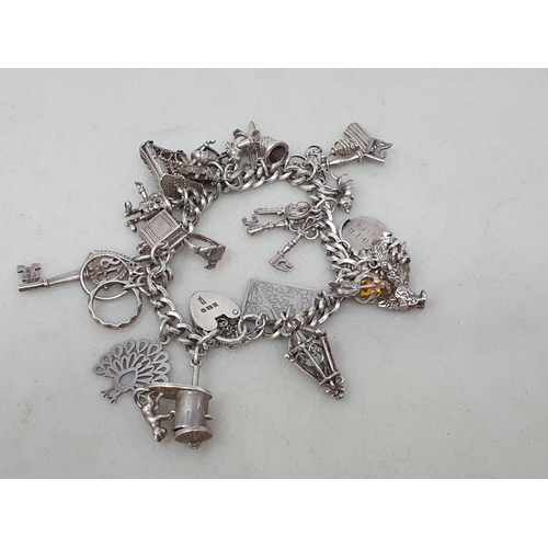 73 - A silver Charm Bracelet with padlock clasp and numerous charms, 56gms
