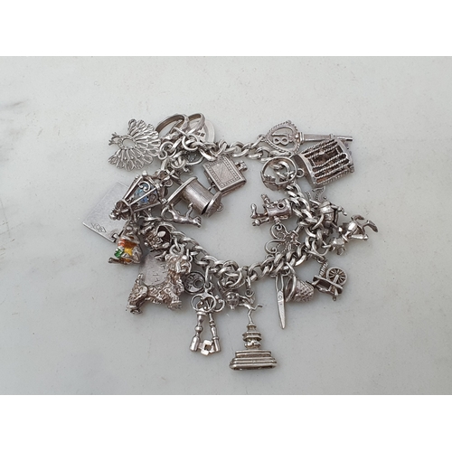 73 - A silver Charm Bracelet with padlock clasp and numerous charms, 56gms