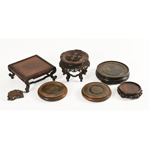 33 - A collection of seven Chinese hardwood stands, to include various types square, round etc and an orn... 