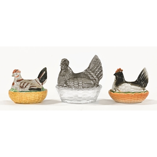 59 - Three hen on nest egg cruets, one ware and another glass and one glass with metal top.  Largest leng... 