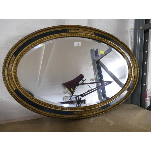 174 - Oval wall mirror with black and gilt frame, length 78 cm