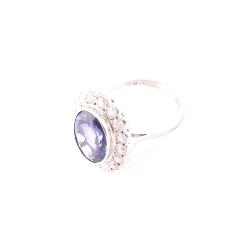 6 - An 18ct white gold, diamond, and tanzanite ring, set with a mixed oval-cut tanzanite, of approximate... 