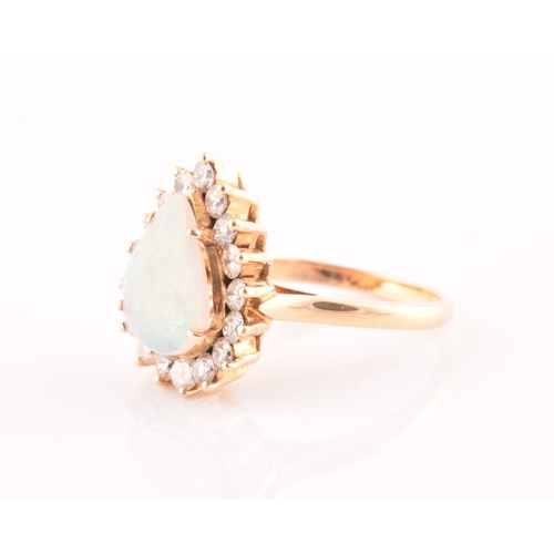 18 - An 18ct yellow gold, diamond, and opal ring, set with a teardrop shaped opal, within a border of rou... 