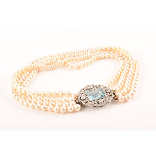 29 - A pearl choker necklace set with a diamond and aquamarine clasp, the quadruple strands formed of rou... 