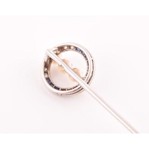 32 - Cartier. A white gold, diamond, and sapphire stick pin, the circular mount inset with calibre-set sa... 